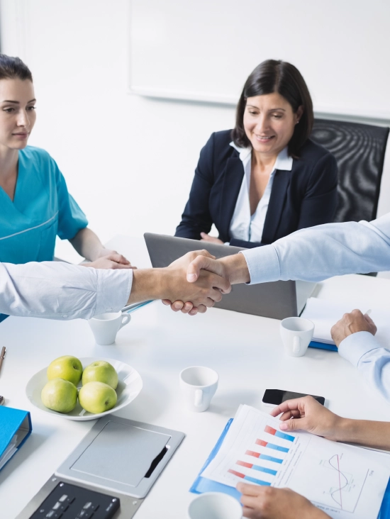 Healthcare administrators and medical billing professionals shaking hands during a partnership meeting